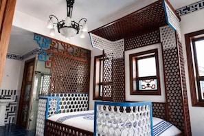 A room with a bed, a window, and a decorative wooden partition.