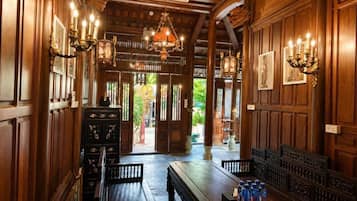 Un interior de madera con una larga mesa, bancos, candelabros y cuadros en las paredes.