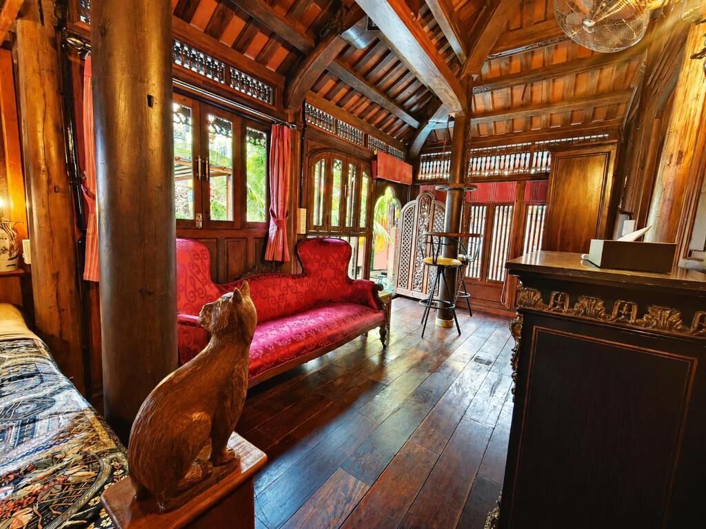 A wooden interior with a red sofa, a wooden cabinet, and a cat statue.