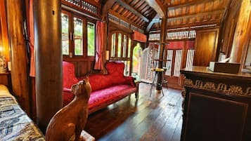 A wooden interior with a red sofa, a wooden cabinet, and a cat statue.