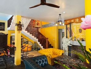 A room with a staircase, a sofa, a table, and a decorative wall.