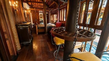 A wooden interior with a central column, a bar area, and a view through large windows.