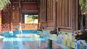 A pool area with decorative lion heads and a traditional architectural style. - Thien Y Villas (Phu Xuan)