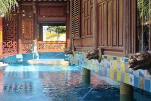 Ein Poolbereich mit dekorativen Löwenköpfen und traditioneller Architektur.