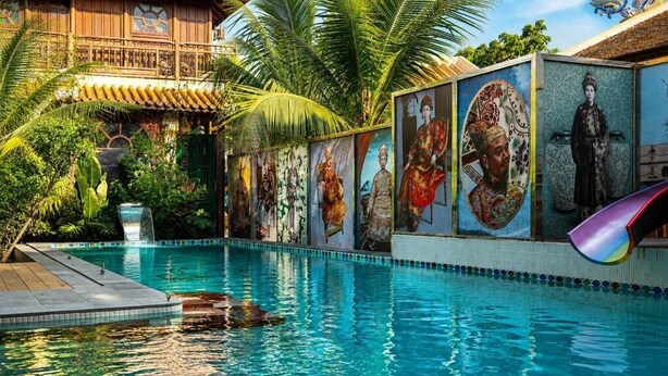 A swimming pool with a mural of historical figures and a slide. - Thien Y Villas (Phu Xuan)