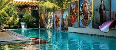 A swimming pool with a mural of historical figures and a slide.