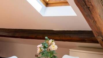 A room with a skylight, a round table with chairs, and a potted plant.