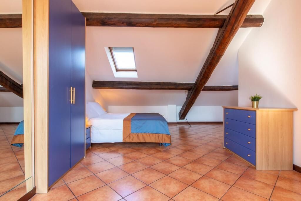 A bedroom with a bed, a wardrobe, a desk, and a small window.