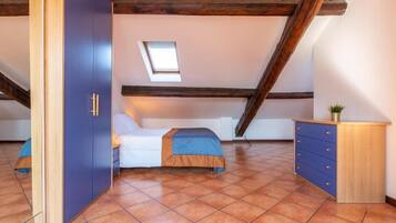 A bedroom with a bed, a wardrobe, a desk, and a small window.