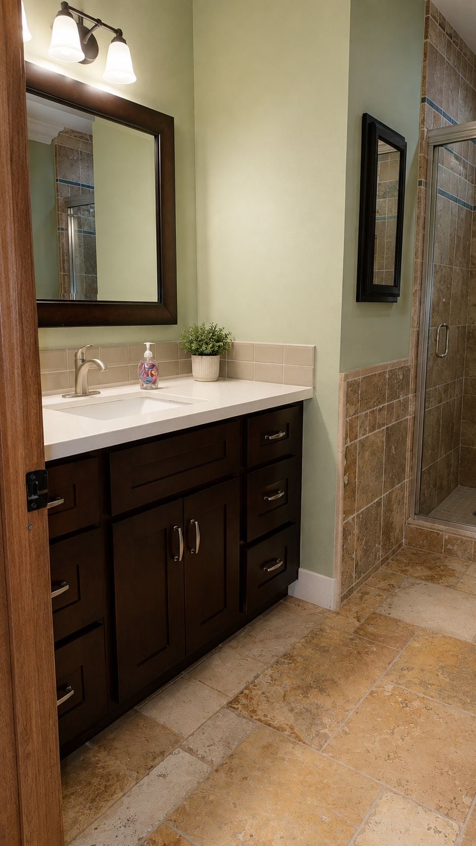 A bathroom with a sink, mirror, cabinet, and shower area.