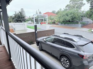 A gray SUV parked on a wooden deck with a view of a residential street and houses in the background. - Harvey’s Beach House Close to South Beach (South Fremantle)