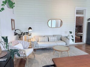 A living room with a sofa, armchair, coffee table, and a floor lamp. - Harvey’s Beach House Close to South Beach (South Fremantle)