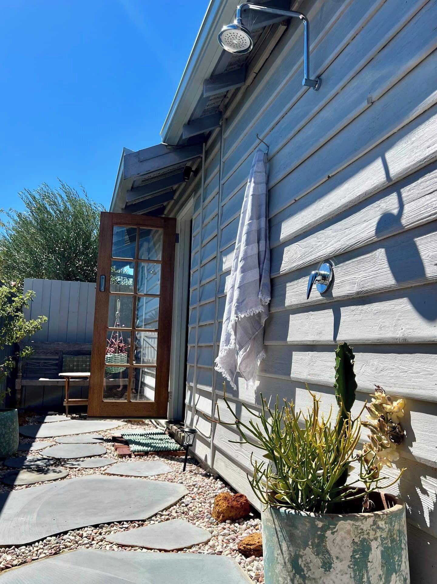 A wooden house with a glass door, a towel hanging on the wall, and a potted plant.