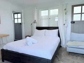 A hotel room with a bed, a bedside table, a chair, and a window with blinds. - South Beach Hideaway Studio- Close to Beach (South Fremantle)