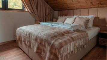 A bedroom with a wooden ceiling, a bed with a white and brown blanket, and a nightstand with a lamp.