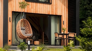 Una casa de madera con una mecedora, una mesa con sillas y un pequeño jardín.