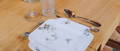 A dining table set with plates, cutlery, glasses, and a vase.
