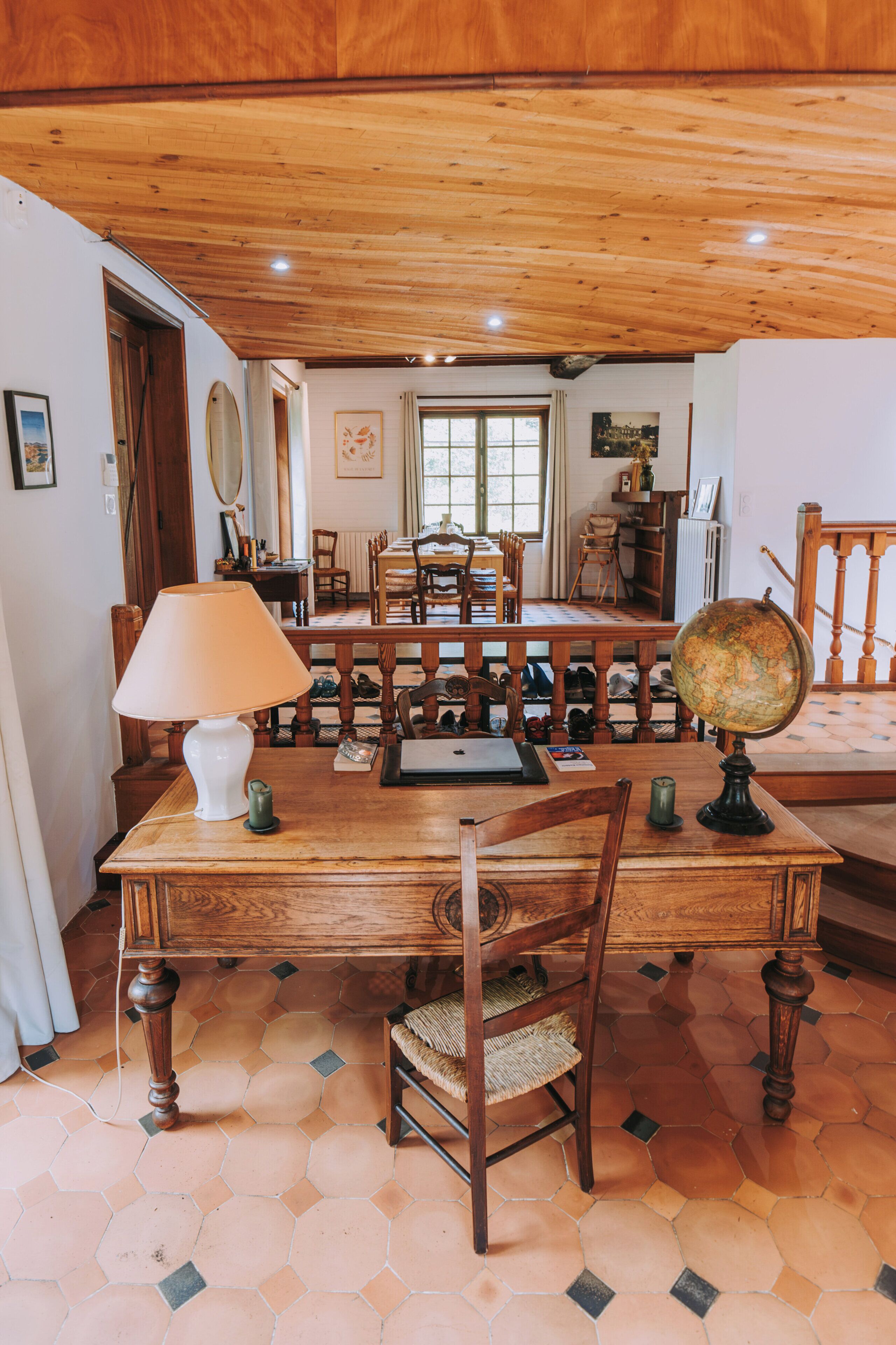 Een eethoek met een houten tafel, stoelen, een wereldbol en een lamp.