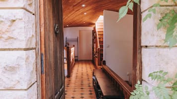 Un couloir avec un plafond en bois, des murs en pierre et un sol carrelé.