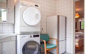 Ein kleiner Waschraum mit Waschmaschine, Trockner und einem Stuhl.