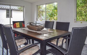 A dining area with a wooden table, woven chairs, and a stone bowl centerpiece. - 3 bedroom amazing home in Borrby (Borrby)