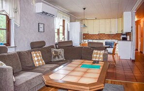 A living room with a sofa, a coffee table, and a kitchen in the background. - 3 bedroom amazing home in Borrby (Borrby)