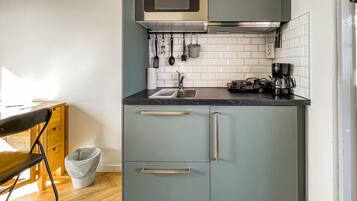 A compact kitchen with a microwave, sink, and coffee maker.