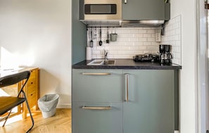 A compact kitchen with a microwave, sink, and coffee maker.