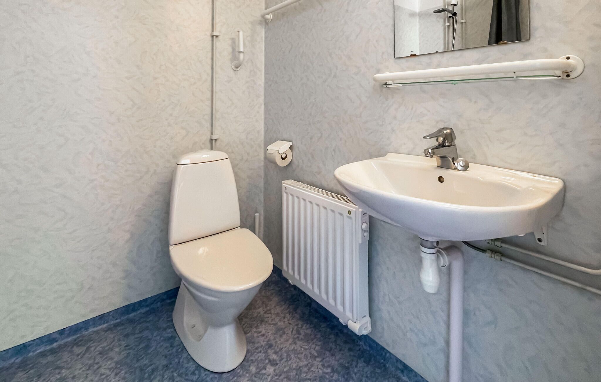 A bathroom with a toilet, a sink, a mirror, and a towel rack.