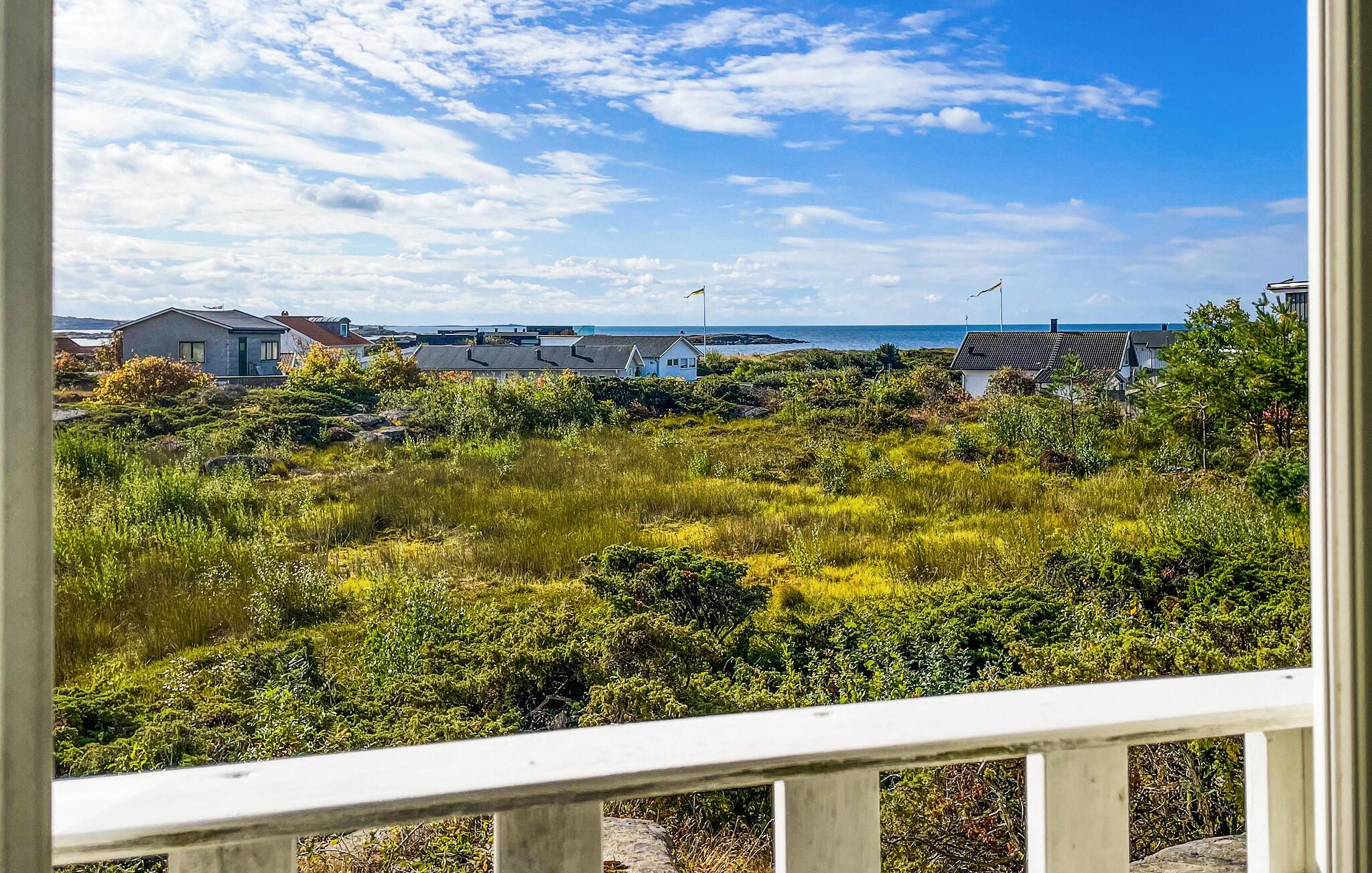 A coastal residential area with houses, a grassy field, and a clear sky.
