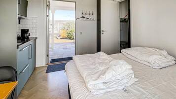 A hotel room with a bed, a desk with a coffee maker, a wardrobe, and a view of the outdoors.
