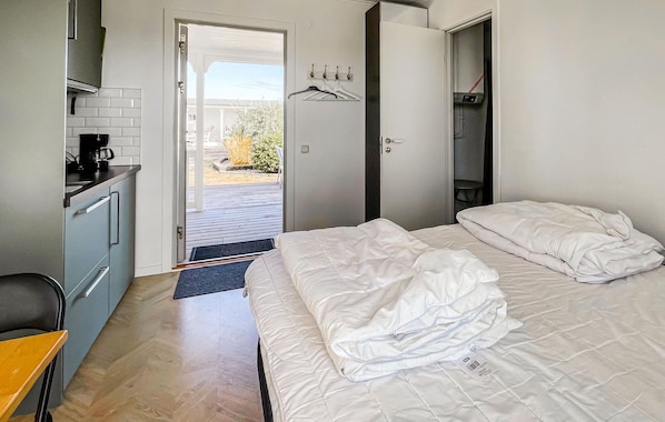 A hotel room with a bed, a desk with a coffee maker, a wardrobe, and a view of the outdoors.