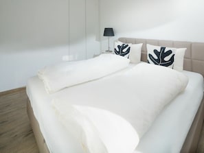 Ein ordentlich bezogenes Bett mit einer großen weißen Decke und zwei Kissen mit Blattmuster.