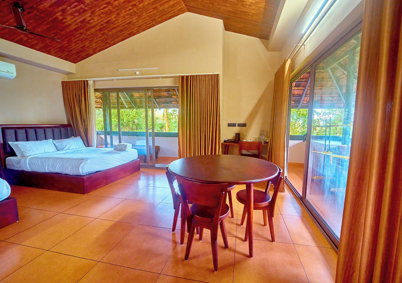 Un dormitorio con una cama grande, una mesa de comedor con sillas y vistas a través de un ventanal.
