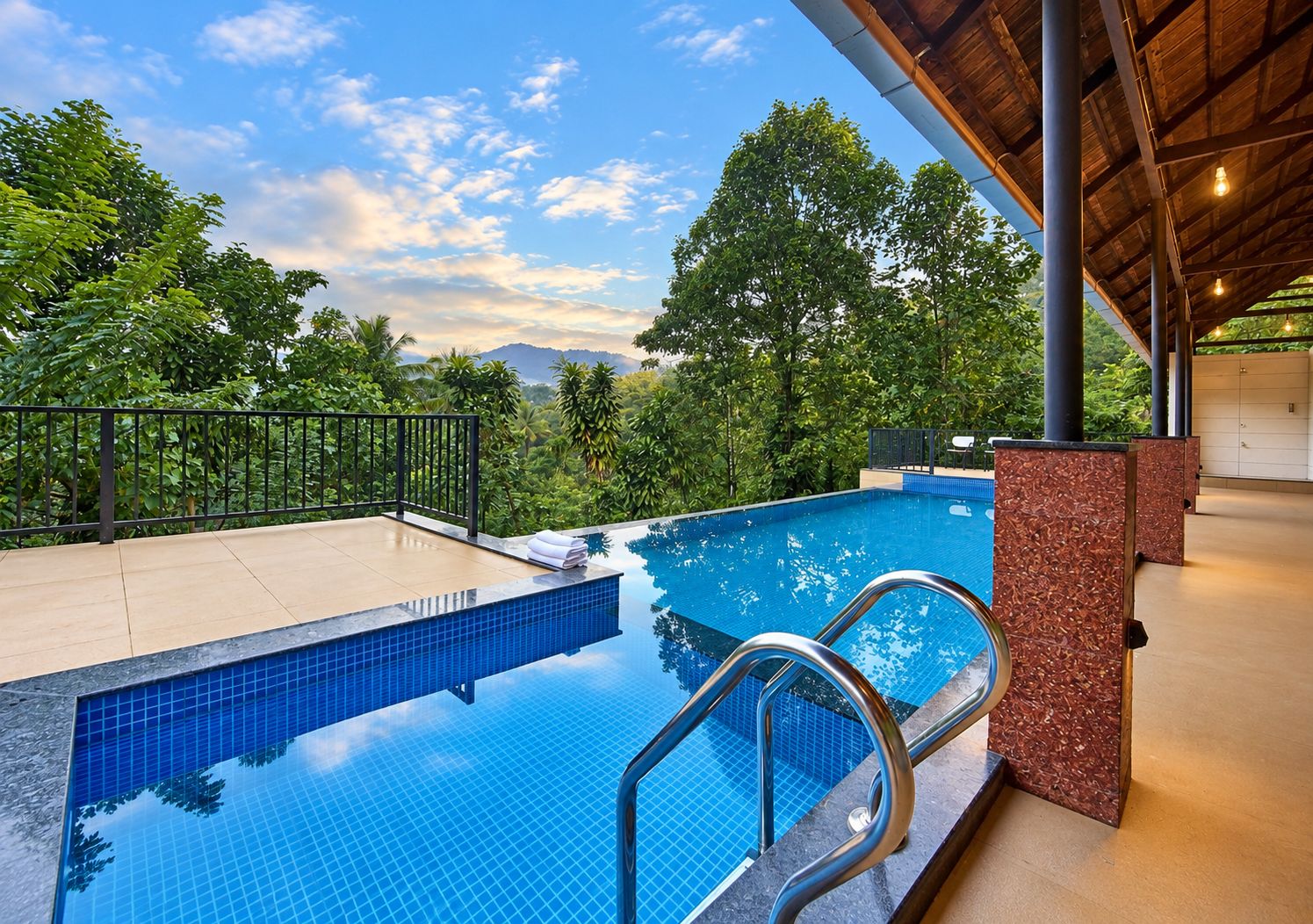 Una piscina con borde de azulejos, rodeada por una cubierta de madera y una barandilla de metal.