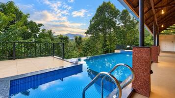 Una piscina con borde de azulejos, rodeada por una cubierta de madera y una barandilla de metal.