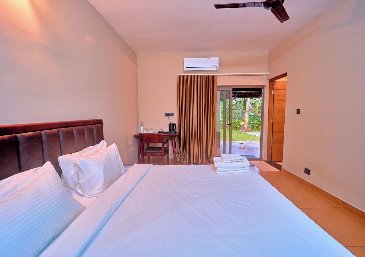 A hotel room with a large bed, a desk, and a view of the outdoors.