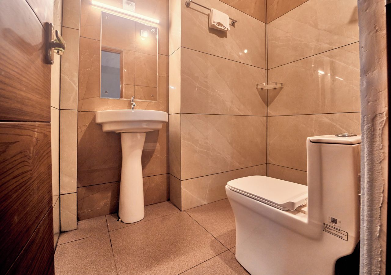 Une salle de bain avec un lavabo sur colonne, des toilettes et un miroir.