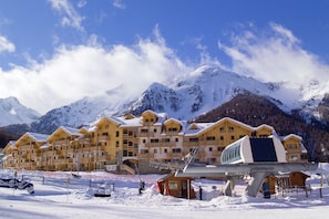 A snow-covered mountain resort with wooden buildings and a ski lift. - Appart cosy et charmant, coeur de la station (Les Orres)