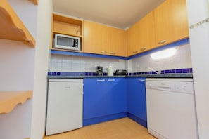 A compact kitchen with wooden cabinets, a microwave, a coffee maker, a toaster, and a dishwasher. - Appart cosy et charmant, coeur de la station (Les Orres)