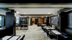 Un restaurant avec des tables et des chaises, un comptoir et une vue sur l’extérieur par les fenêtres.