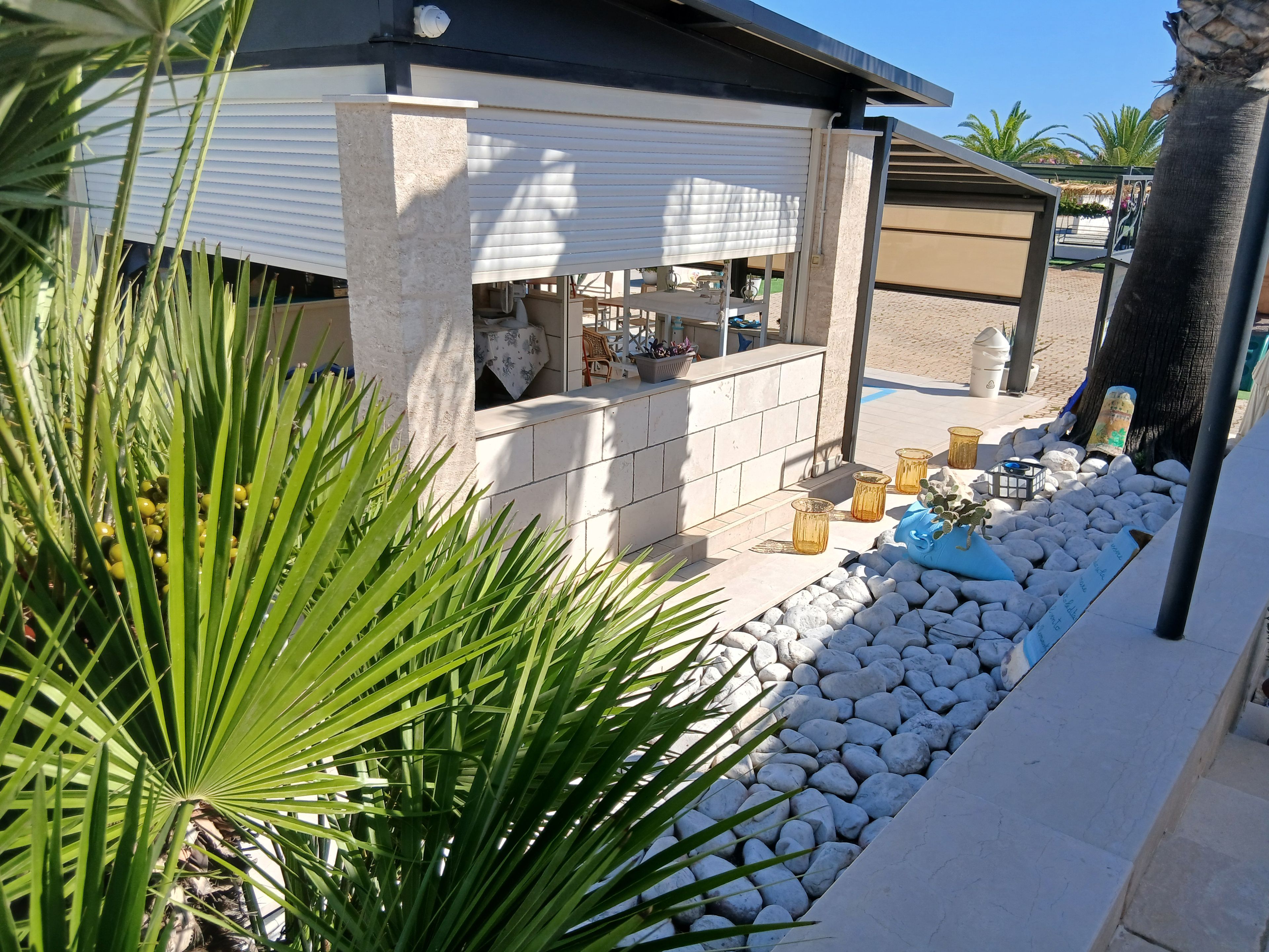 A modern outdoor bar area with a stone counter, seating, and a decorative plant arrangement.