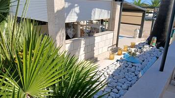 A modern outdoor bar area with a stone counter, seating, and a decorative plant arrangement.