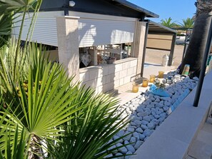A modern outdoor bar area with a stone counter, seating, and a decorative plant arrangement.
