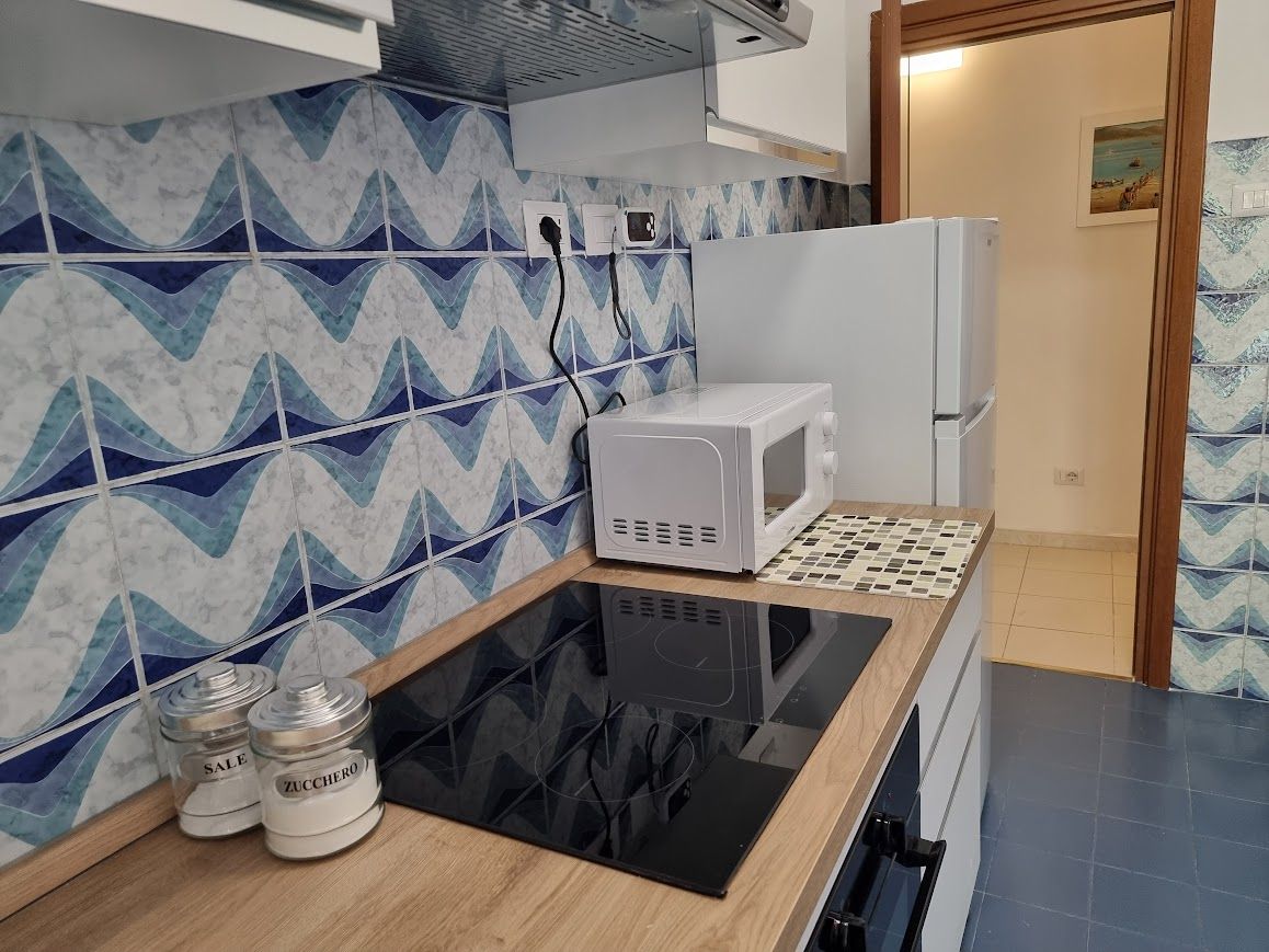 A kitchen with a microwave, a stove, and two jars labeled 'SALE' on the counter.