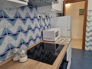 A kitchen with a microwave, a stove, and two jars labeled 'SALE' on the counter. - Easy Metro Apartment Rome Boccea (Roma)