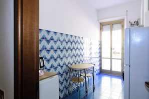 Uma cozinha pequena com painel decorativo, geladeira, pia e janela com persianas.