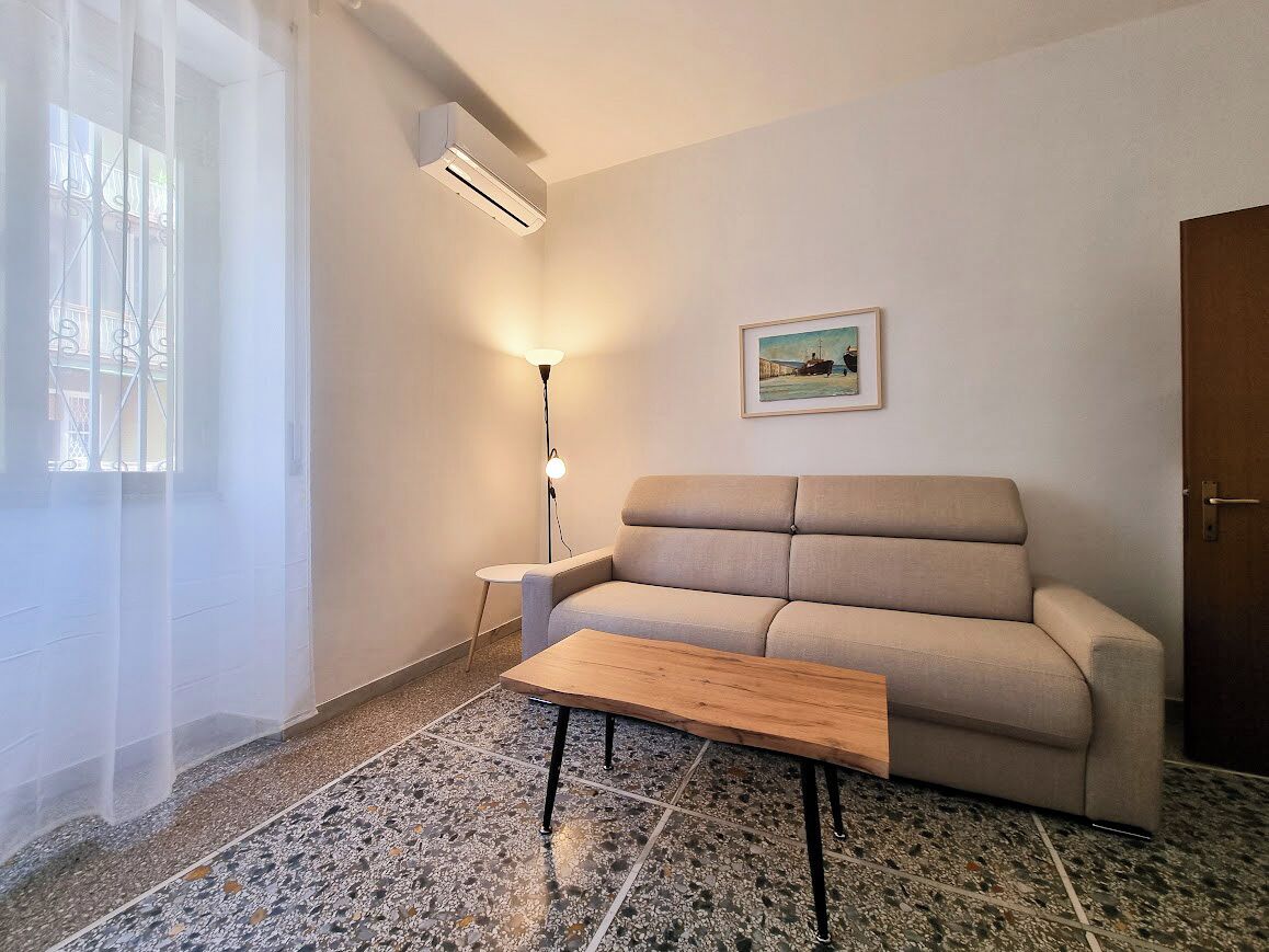 A living room with a sofa, a coffee table, a lamp, and a painting on the wall.