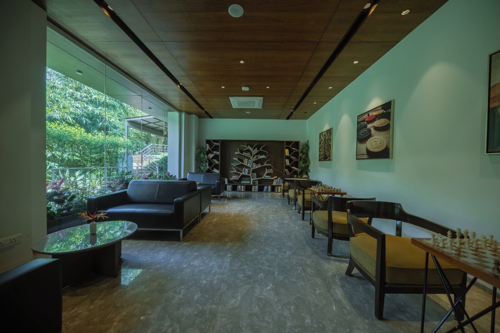 A modern interior with a glass wall, a fireplace, and a chess table.