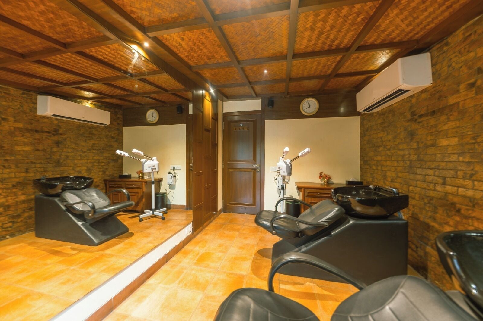 A room with massage chairs, a wooden ceiling, and a brick wall.